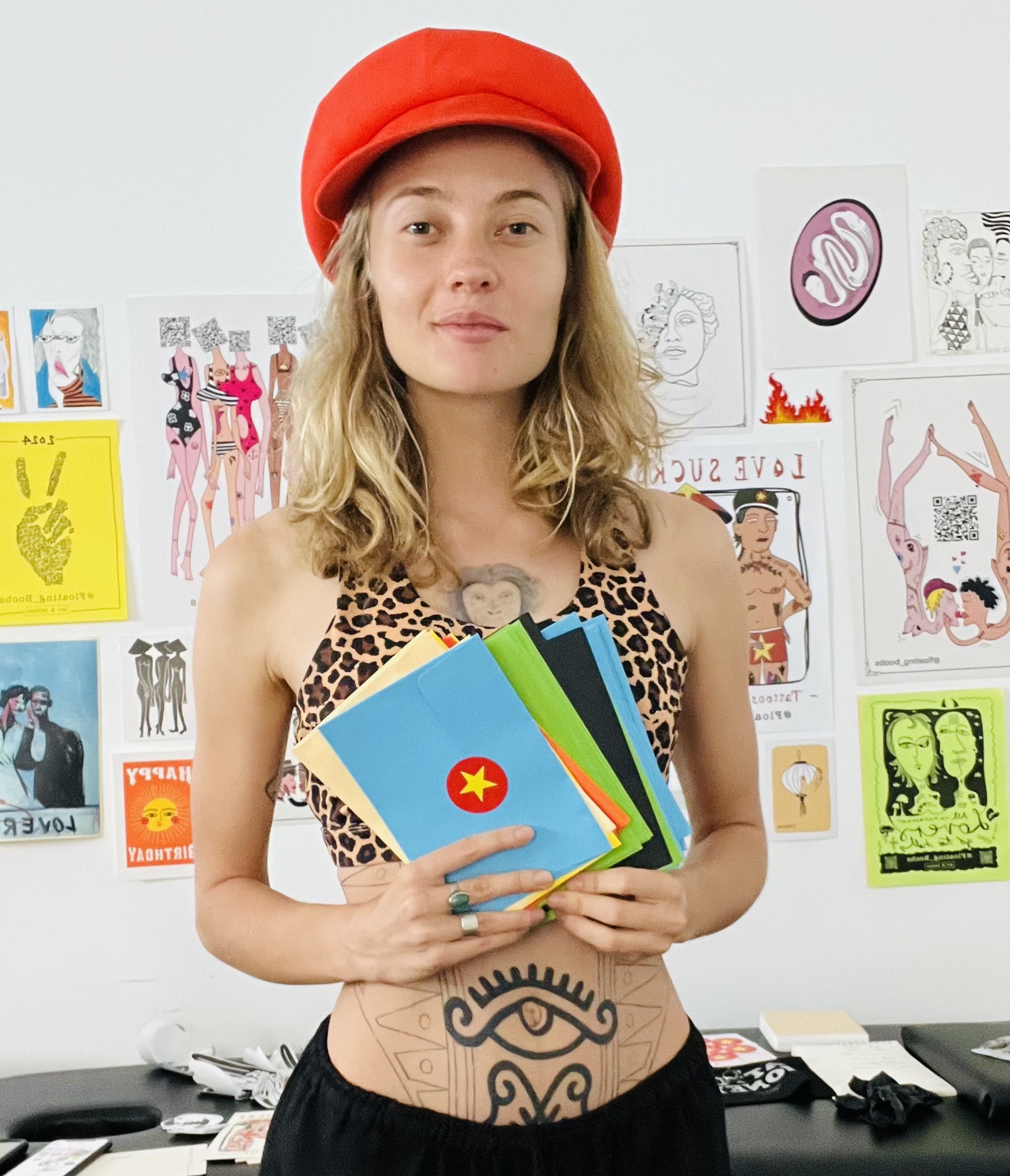 Ela in her Hội An studio holding a stack of orange envelopes
