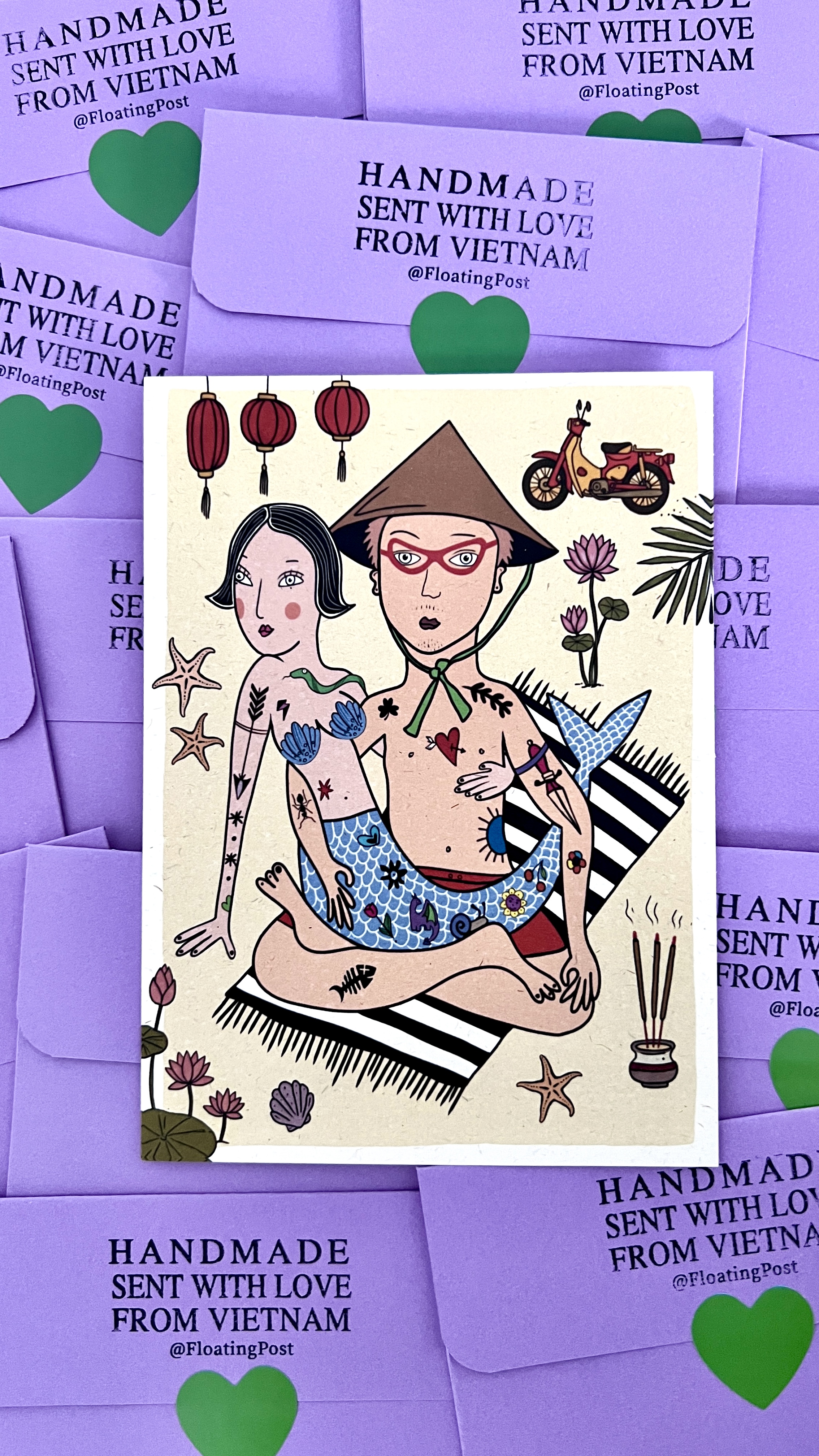 A hand-drawn mermaid couple postcard laid over a stack of lavender Floating Post envelopes stamped Handmade, sent with love from Vietnam